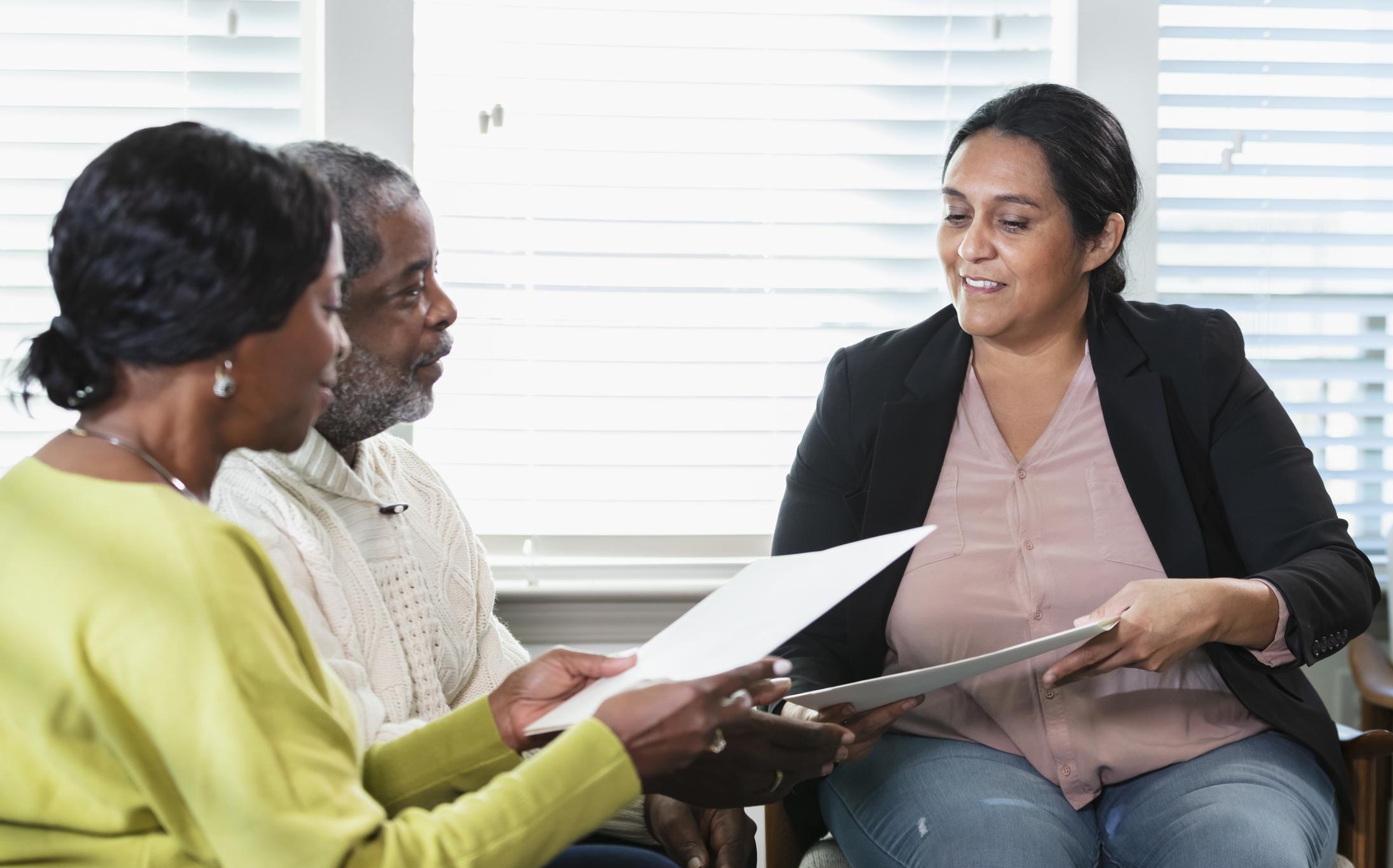 woman explaining to a couple while looking at paper